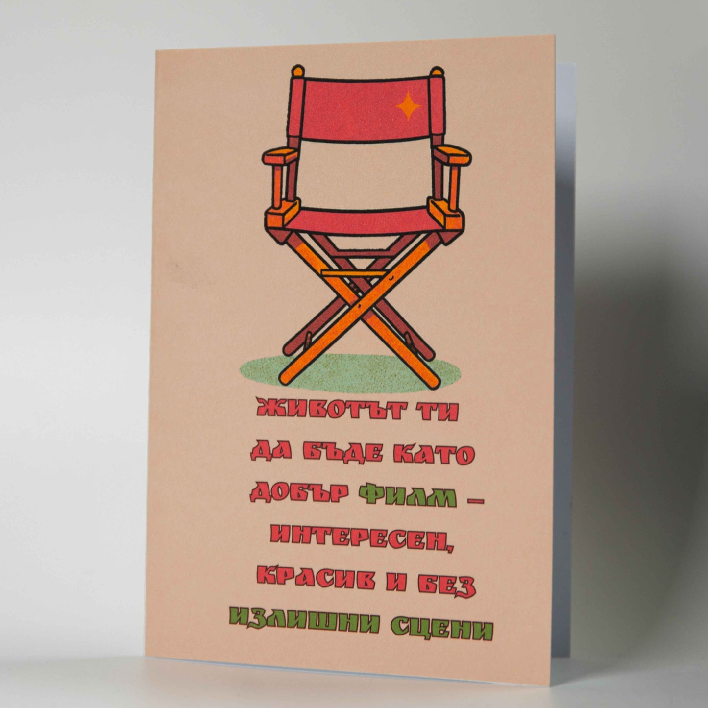 Снимка 1 (Лице): Картичка за рожден ден с червен режисьорски стол и текст за живот като на кино - Картичарница Снимка 2 (Комплект): Оригинална картичка за киноман с плик и послание без излишни сцени